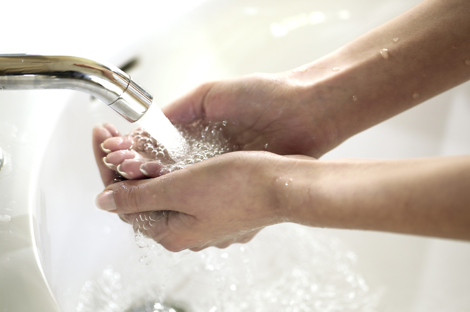 Hände über einem Waschbecken, die fließendes Wasser auffangen